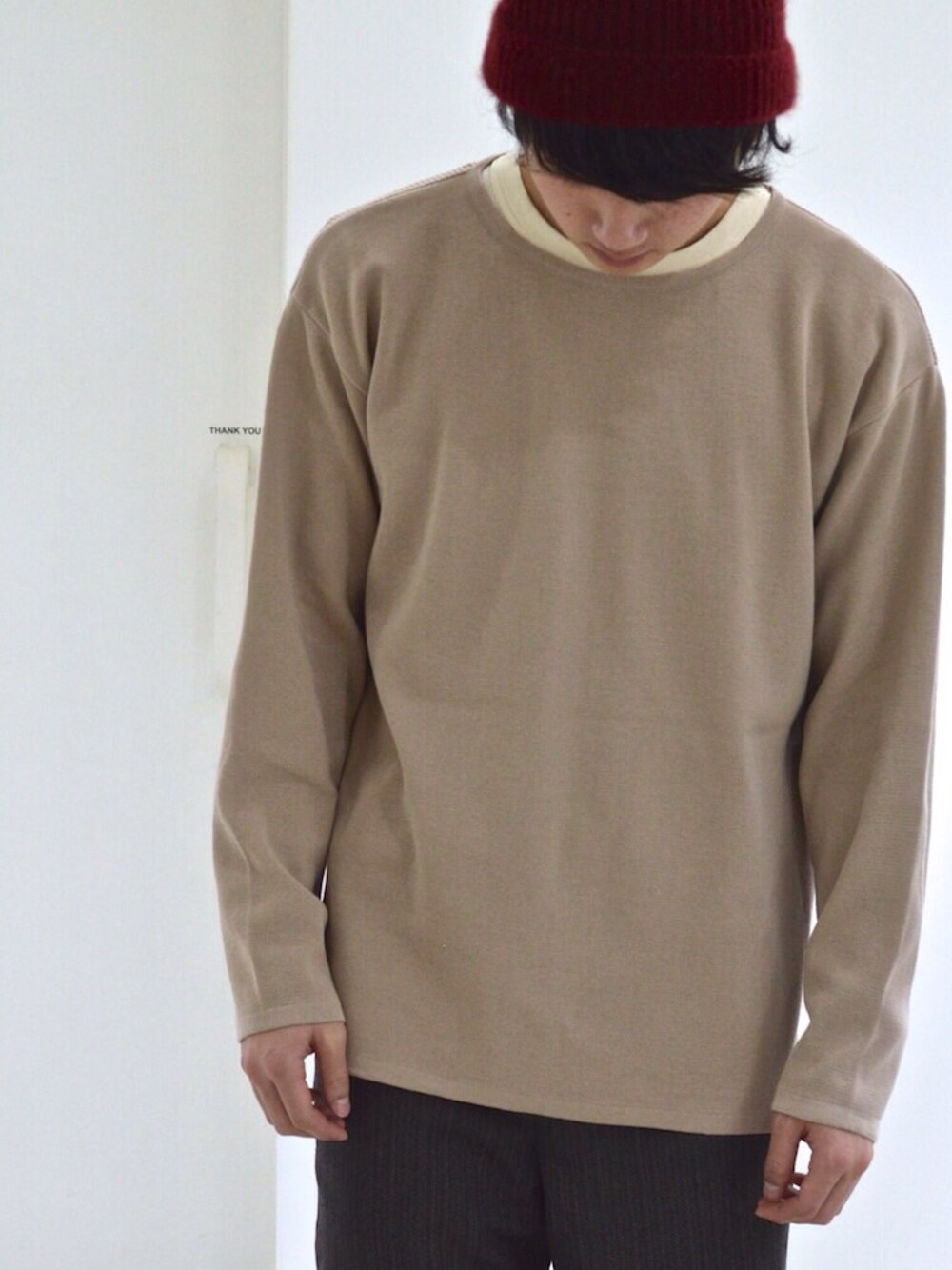 ベージュ系のニット/セーター、ブラウン系のスラックス、レッド系のニットキャップ/ビーニーを着用したメンズの冬コーディネートの1枚目の写真