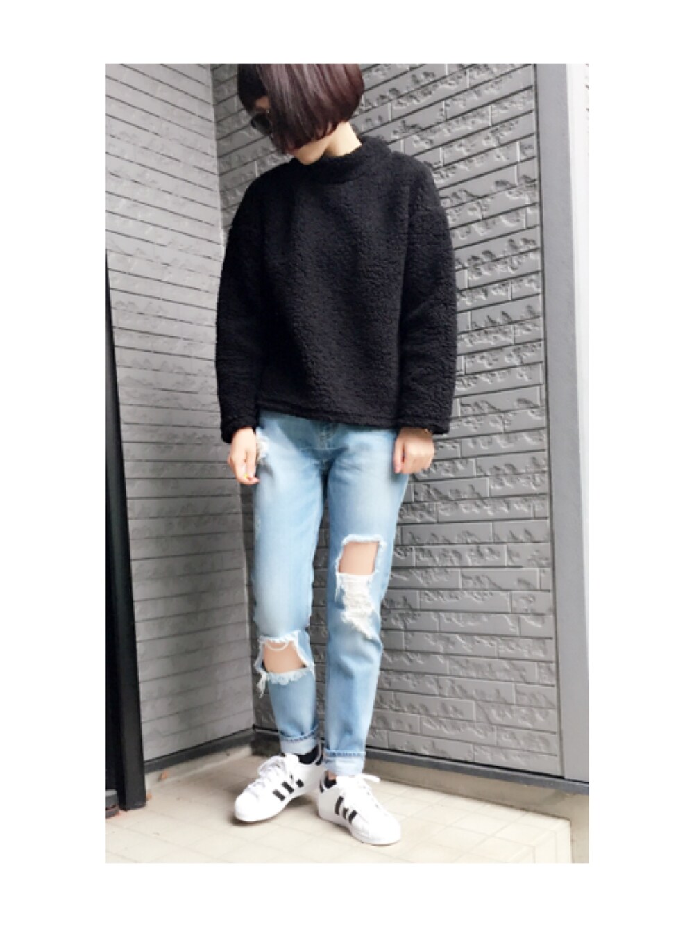 ブラック系のトップス、ブルー系のデニムパンツ、ホワイト系のスニーカーを着用したレディースの冬コーディネートの1枚目の写真