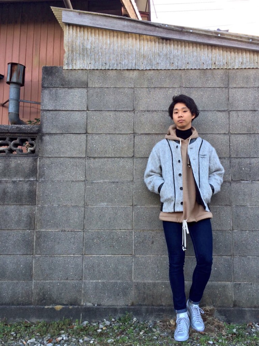 グレー系のブルゾン、ブラウン系のパーカー、シルバー系のスニーカーを着用したメンズの冬コーディネートの1枚目の写真