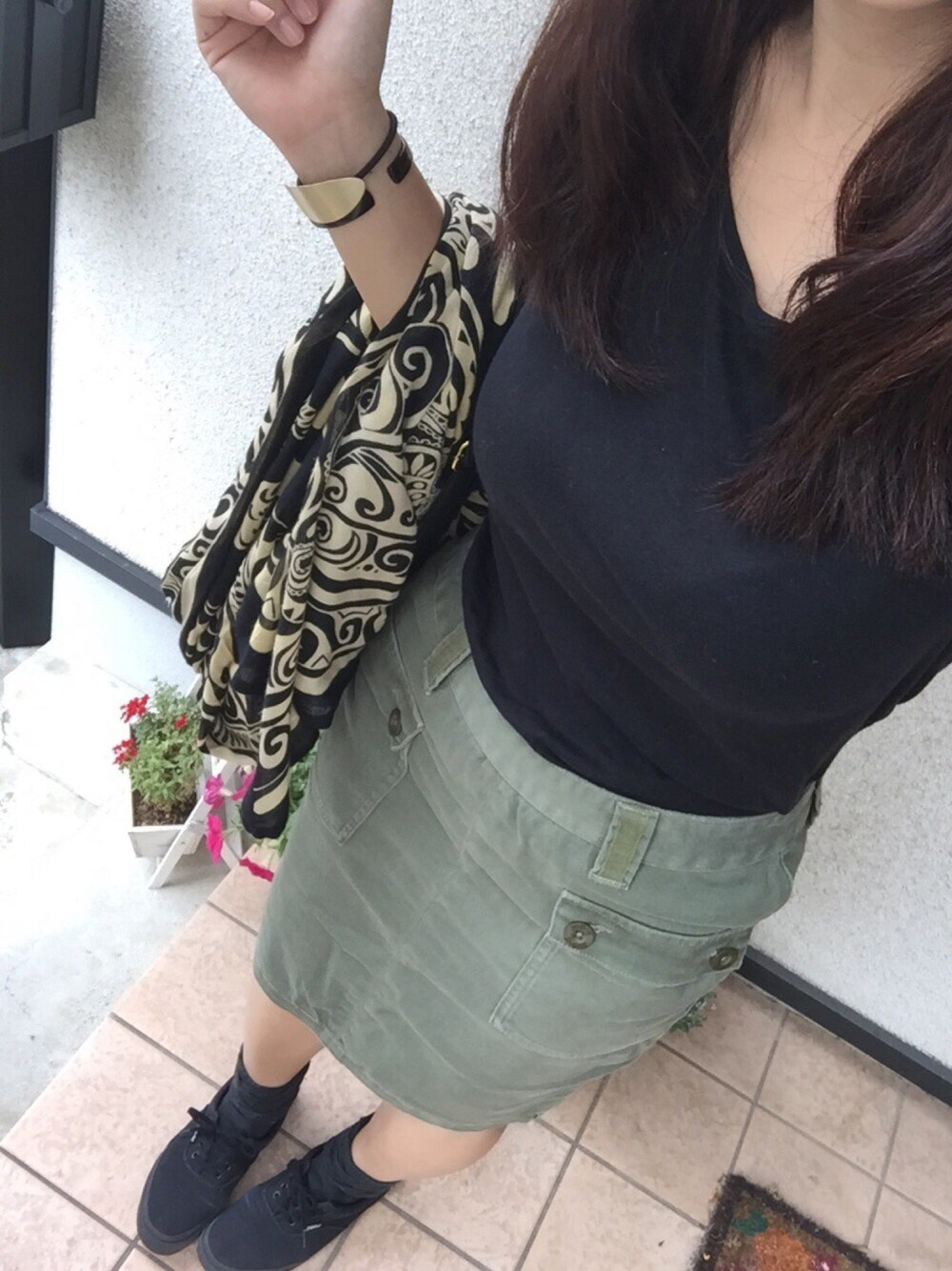 グリーン系のスカート、ブラック系のスニーカー、ブラック系のファッション雑貨を着用したレディースの春コーディネートの1枚目の写真