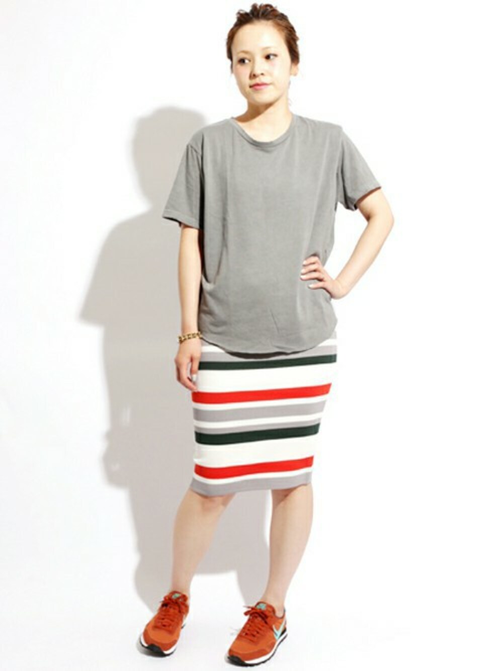 オレンジ系のスニーカー、オレンジ系のスカート、グレー系のTシャツ/カットソーを着用したレディースの夏コーディネートの1枚目の写真