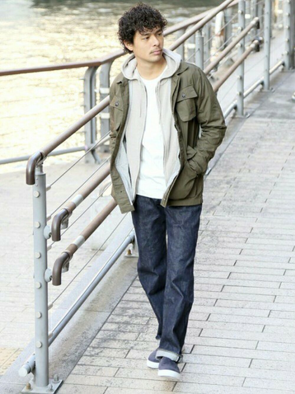 グリーン系のミリタリージャケット、ベージュ系のカーディガン/ボレロ、ブルー系のデニムパンツを着用したメンズの春コーディネートの1枚目の写真