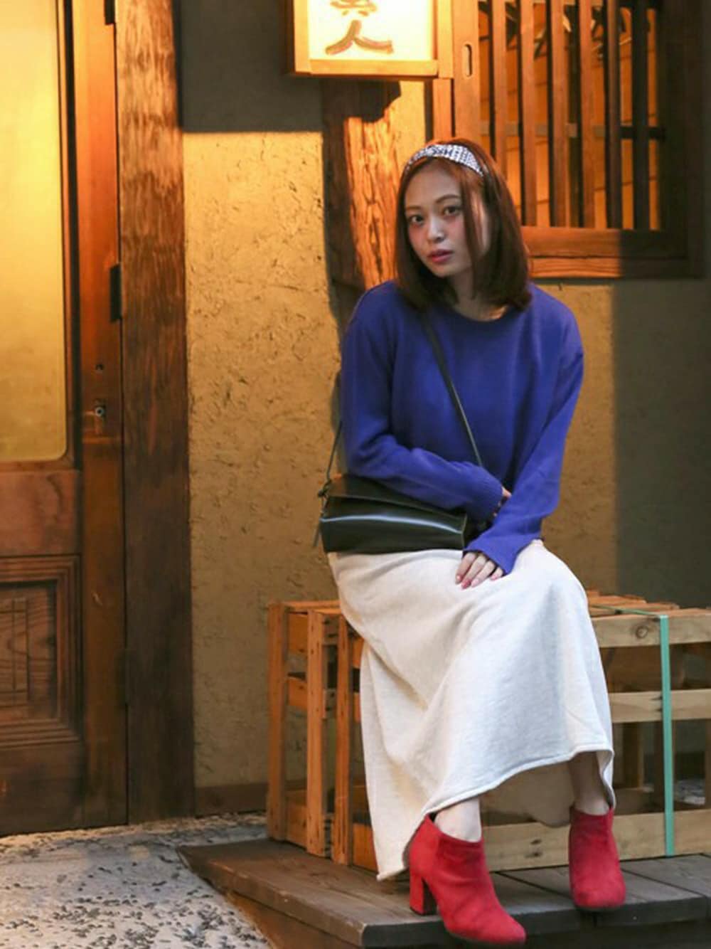 ブルー系のニット/セーター、ベージュ系のスカート、グリーン系のショルダーバッグを着用したレディースの春コーディネートの1枚目の写真