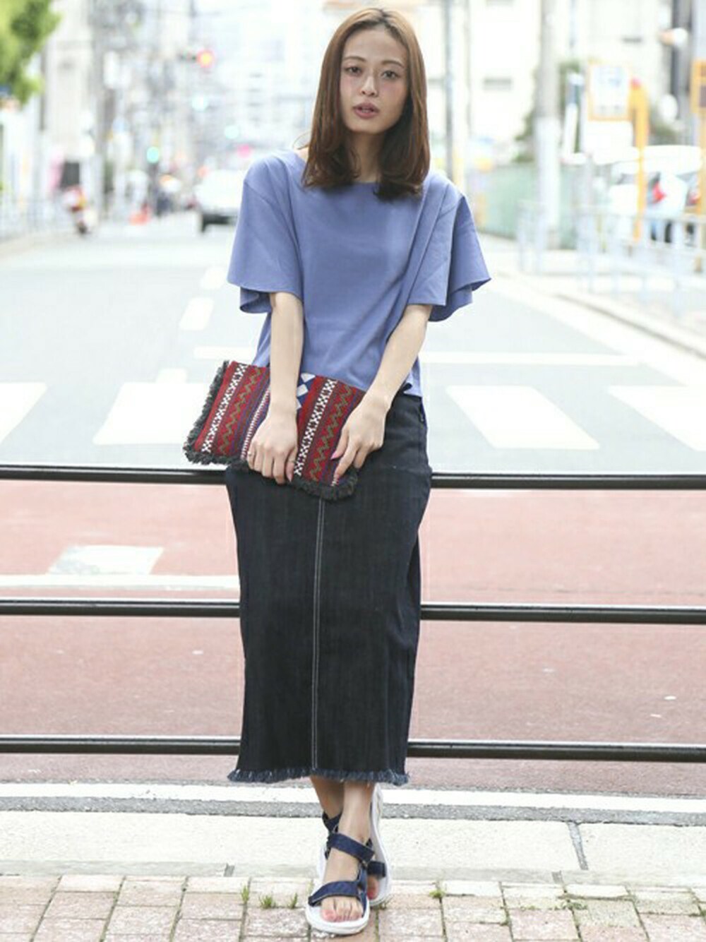 ブルー系のデニムスカート、ブルー系のTシャツ/カットソー、レッド系のクラッチバッグを着用したレディースの春コーディネートの1枚目の写真