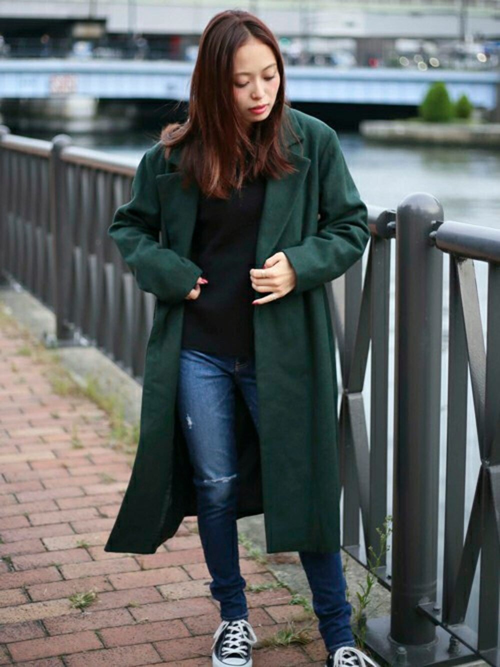 グリーン系のチェスターコート、ブラック系のTシャツ/カットソー、ブルー系のデニムパンツを着用したレディースの秋コーディネートの1枚目の写真