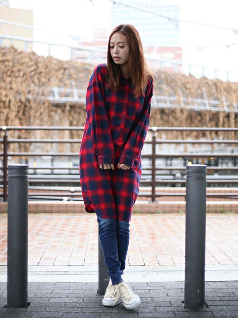 レッド系のシャツワンピース、ブルー系のデニムパンツを着用したレディースの秋コーディネートの1枚目の写真