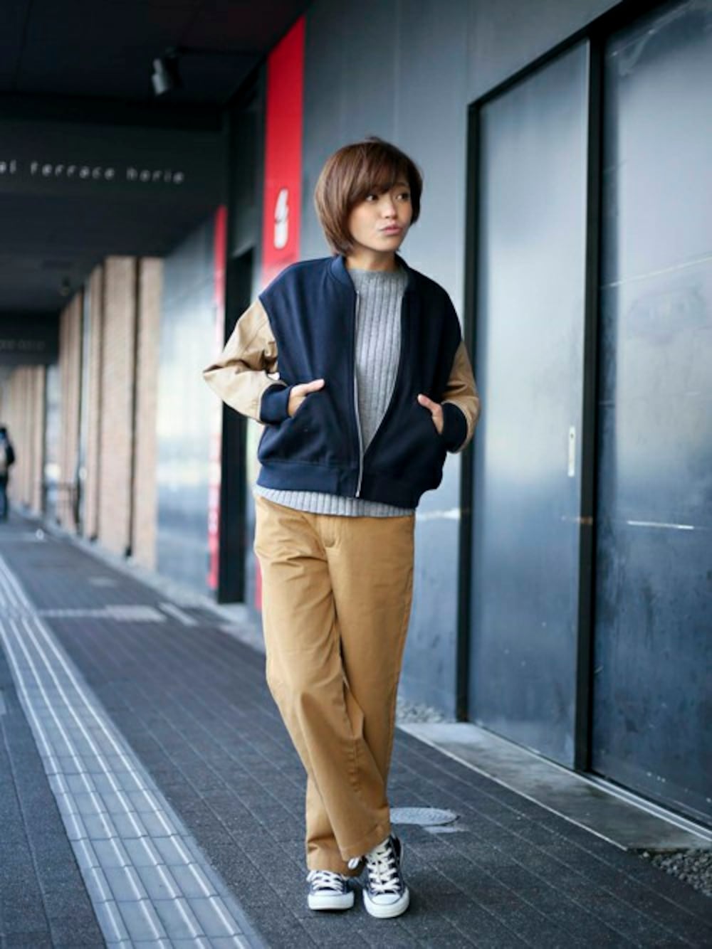 ブルー系のスタジャン、グレー系のニット/セーター、イエロー系のチノパンツを着用したレディースの冬コーディネートの1枚目の写真