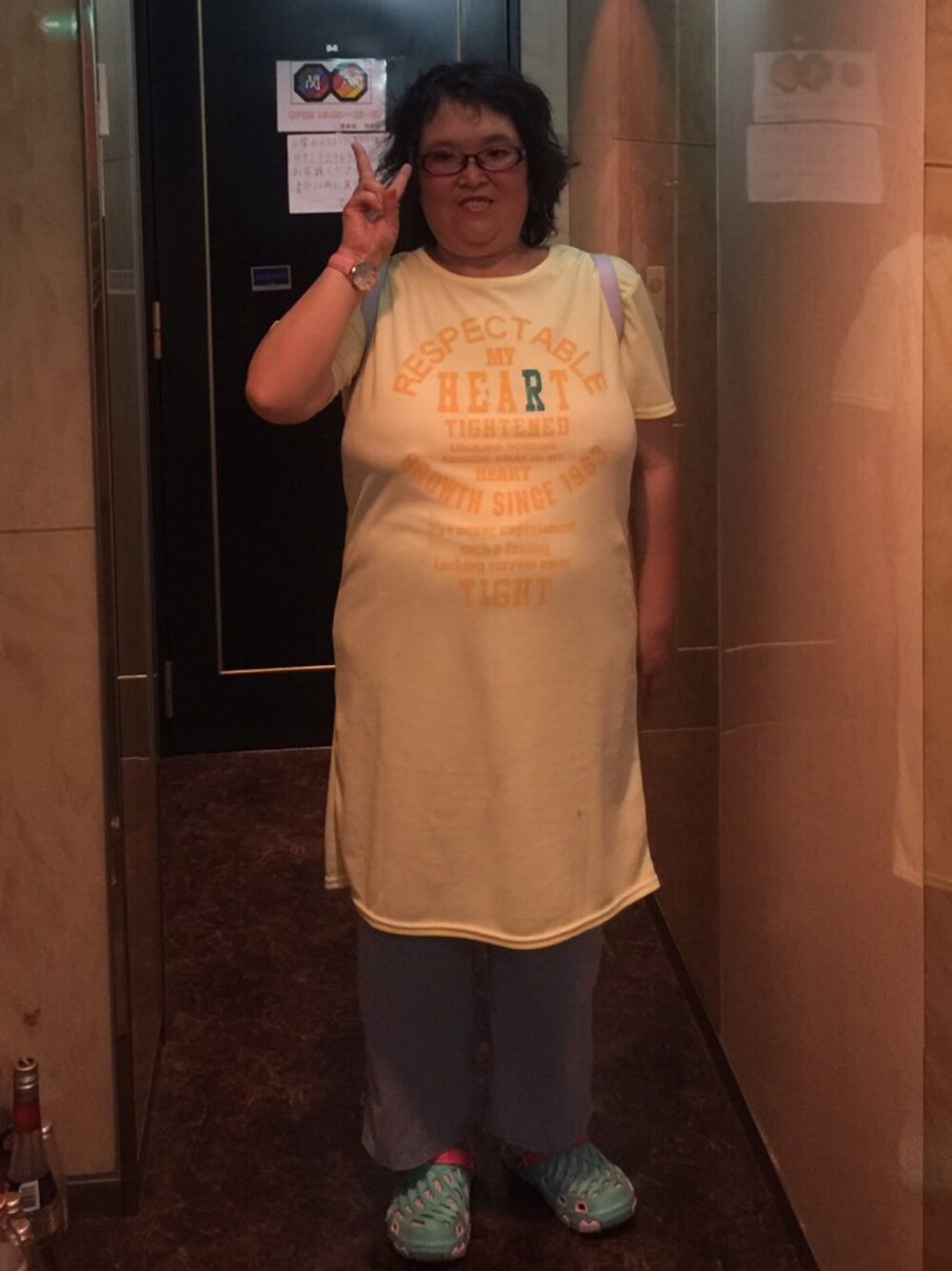 ベージュ系のシャツワンピース、ブルー系のデニムパンツ、ブルー系のサンダルを着用したレディースの春コーディネートの1枚目の写真