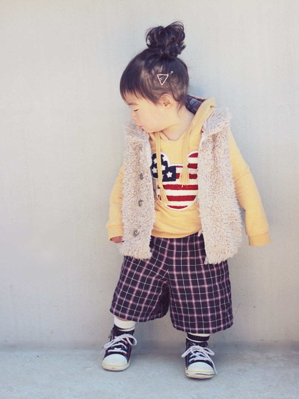 ブルー系のベスト、イエロー系のパーカー、ブラック系のパンツを着用したキッズの冬コーディネートの1枚目の写真