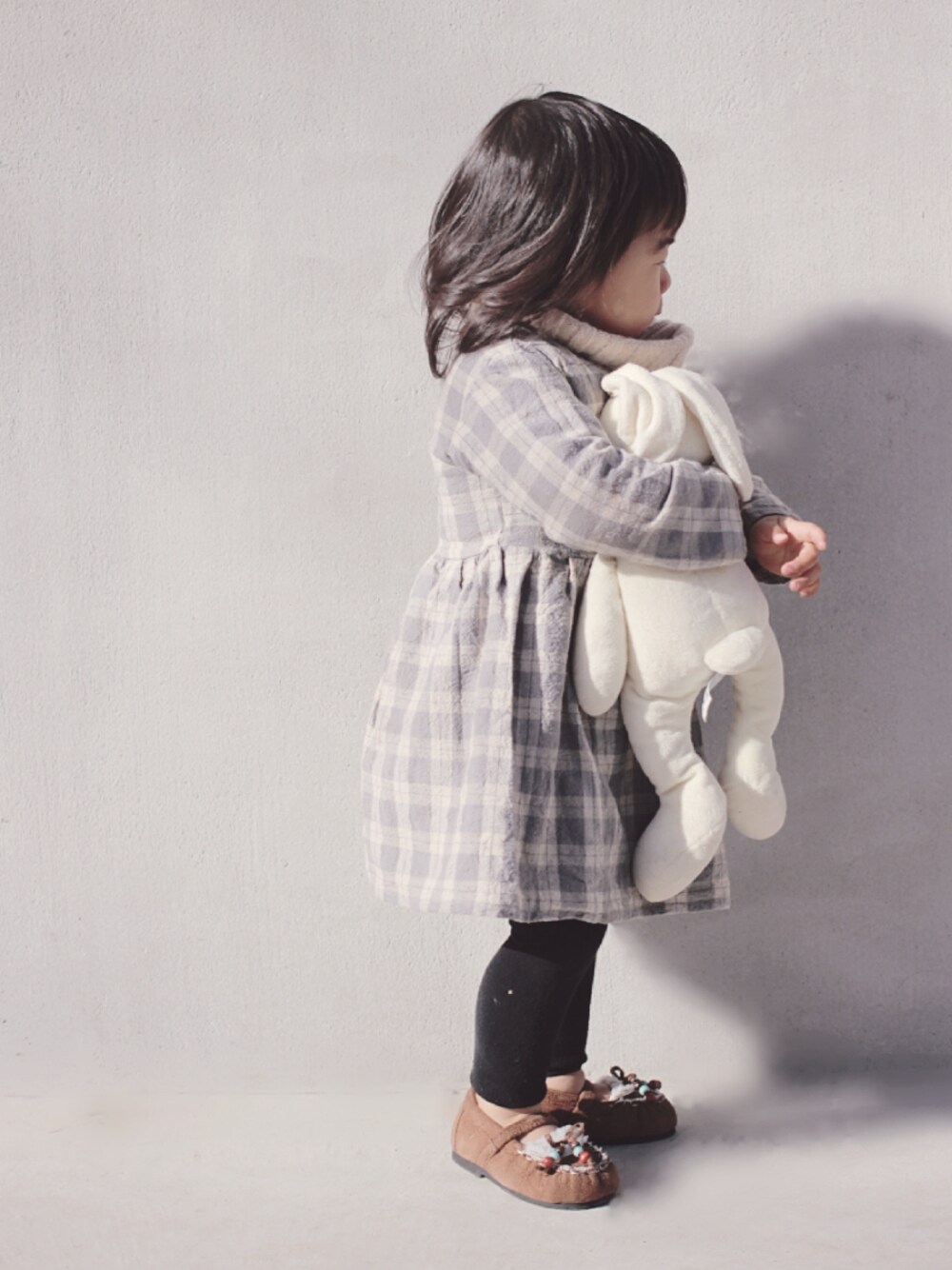 ベージュ系のベスト、グレー系のワンピース、ブラウン系のモカシン/デッキシューズを着用したキッズの冬コーディネートの1枚目の写真