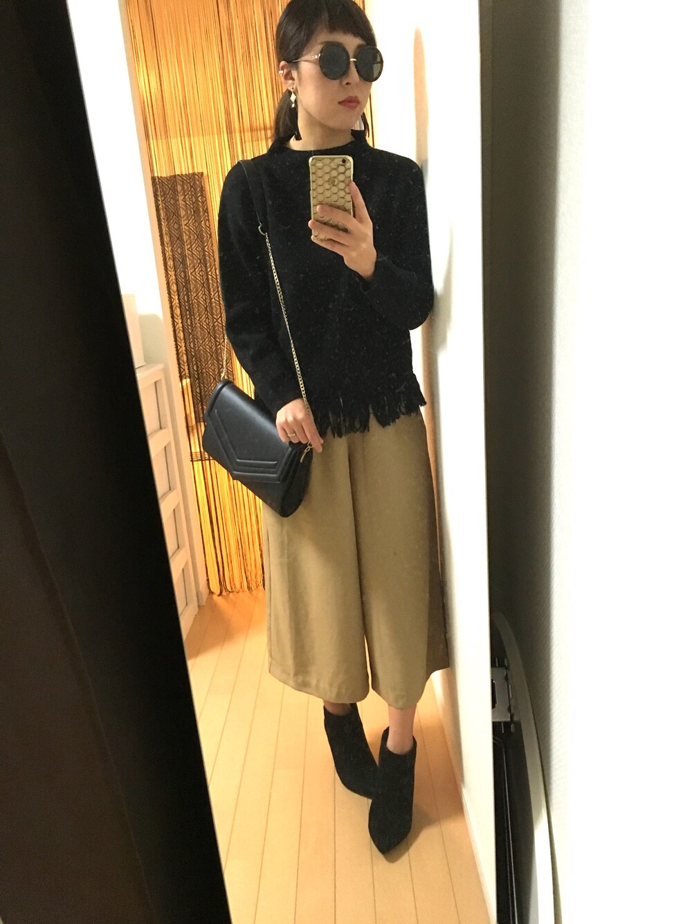 ベージュ系のパンツ、ブラック系のニット/セーター、ブラック系のブーツを着用したレディースの春コーディネートの1枚目の写真