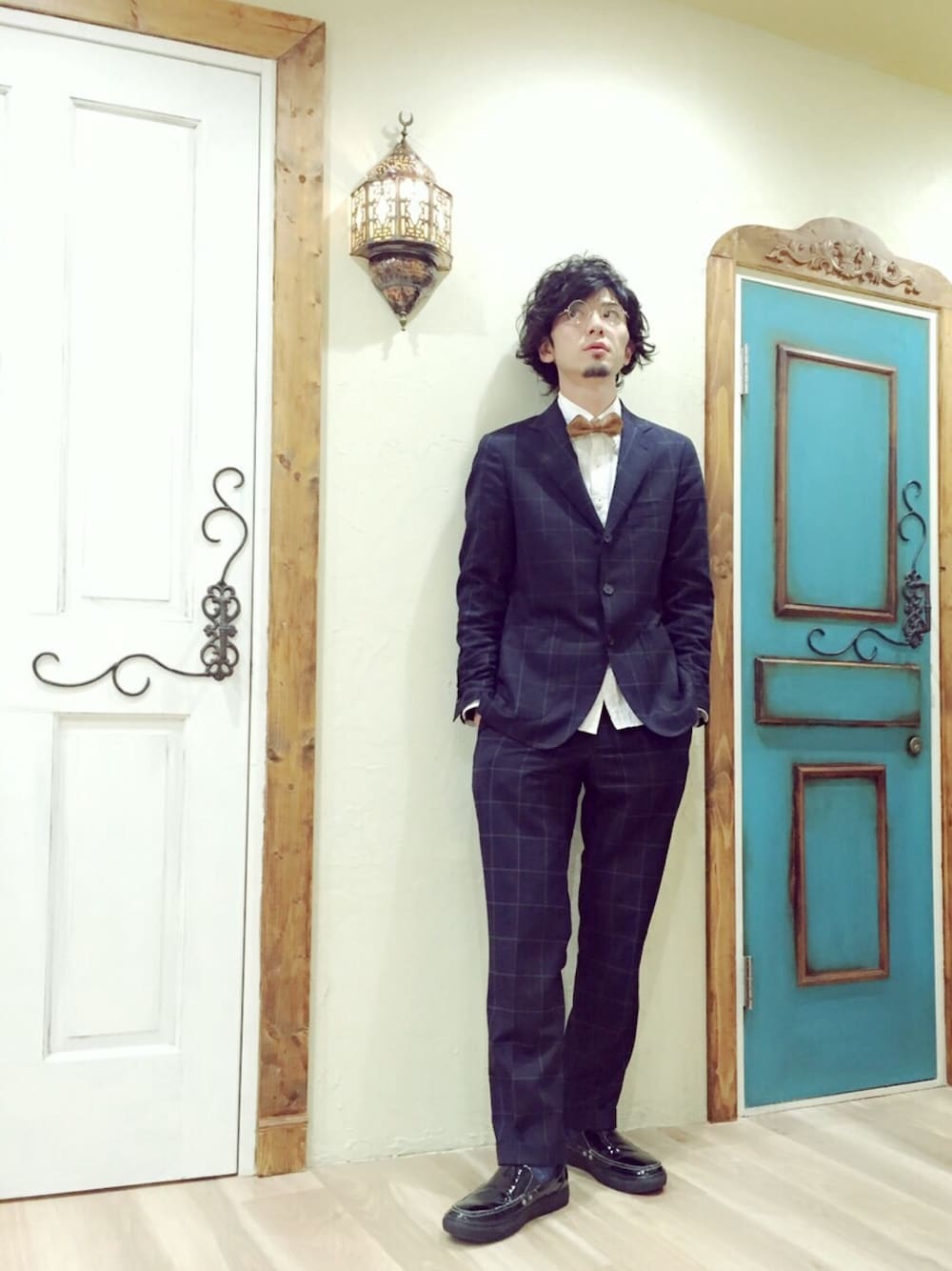 ブラック系のテーラードジャケット、ブラウン系の蝶ネクタイ、ブラック系のスニーカーを着用したメンズの秋コーディネートの1枚目の写真