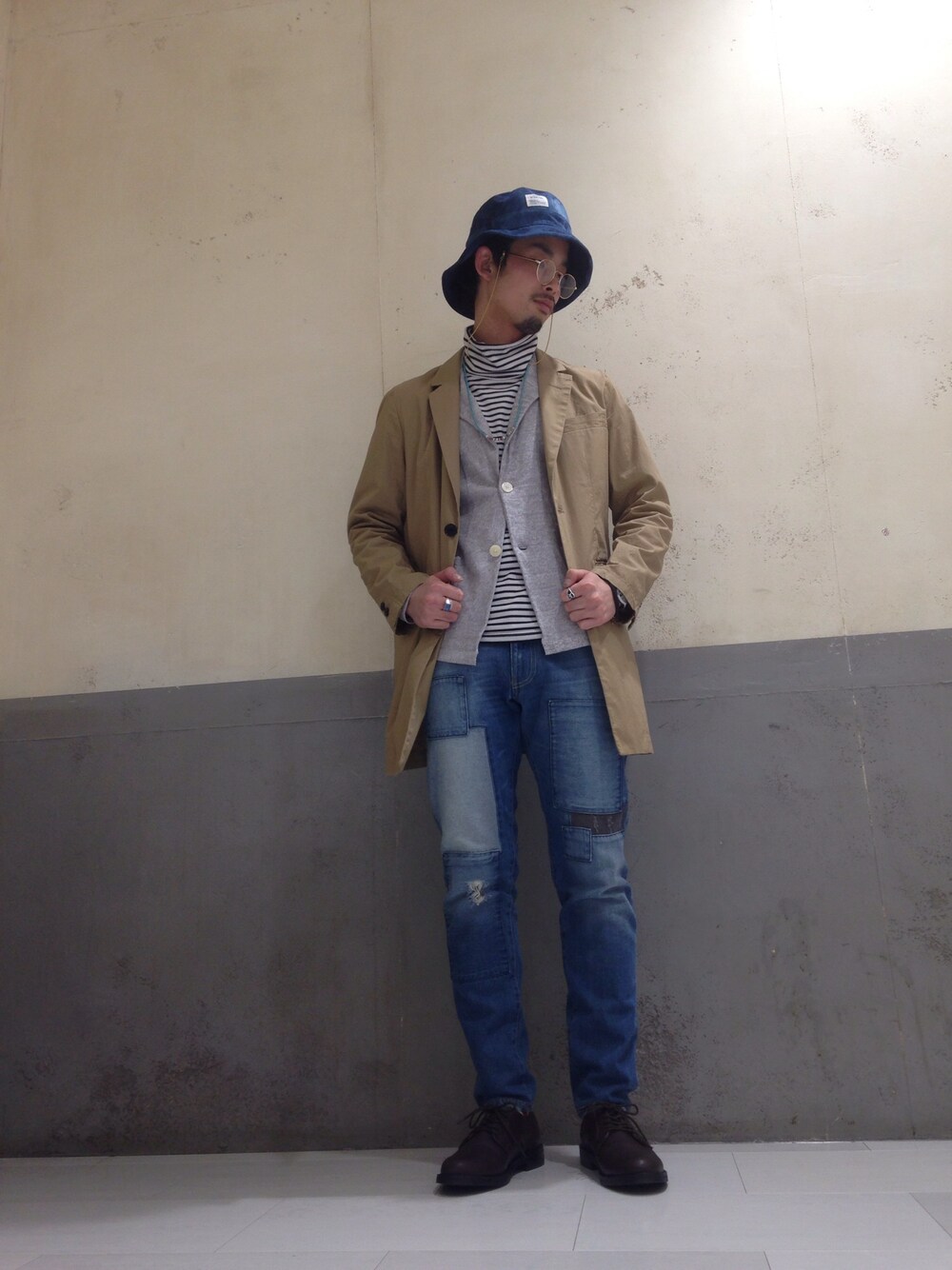 ベージュ系のチェスターコート、グレー系のジャケット/アウター、ブルー系のデニムパンツを着用したメンズの春コーディネートの1枚目の写真