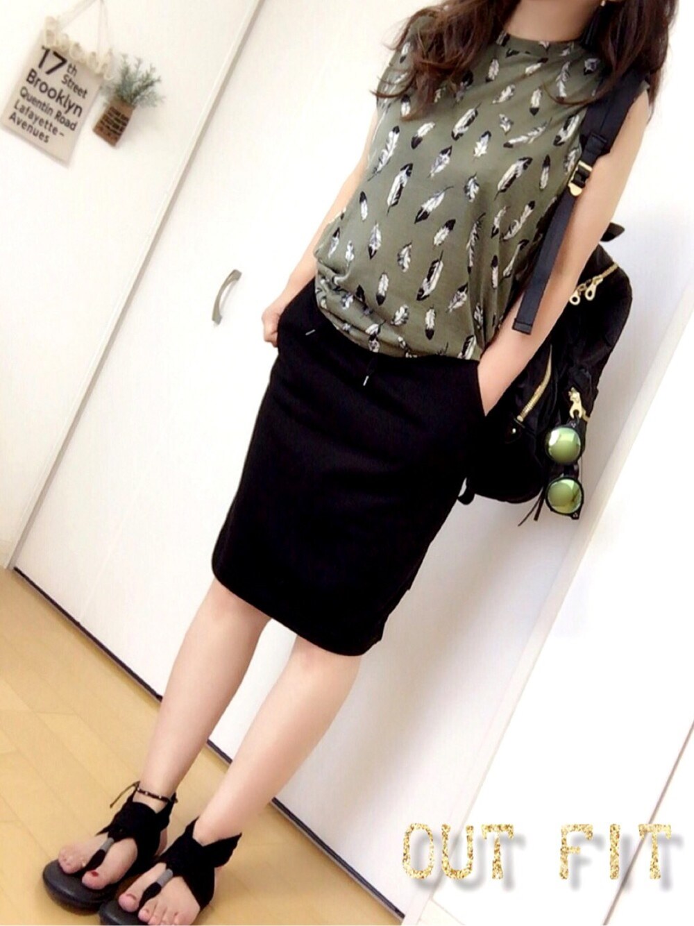 ブラック系のバックパック/リュック、グリーン系のTシャツ/カットソー、ブラック系のサンダルを着用したレディースの夏コーディネートの1枚目の写真