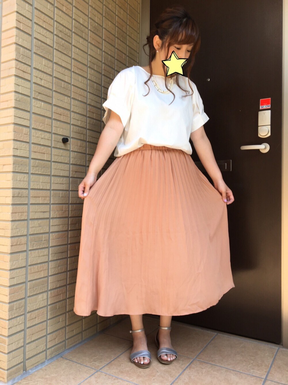 ホワイト系のトップス、ピンク系のスカート、シルバー系のサンダルを着用したレディースの夏コーディネートの1枚目の写真