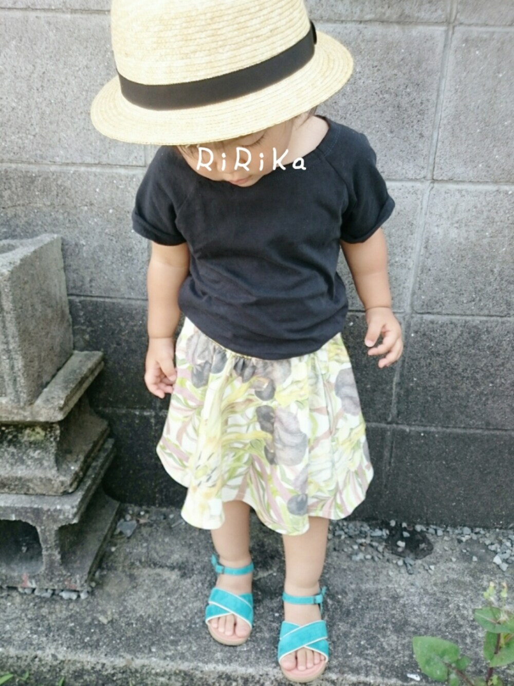 ブラック系のTシャツ/カットソー、イエロー系のスカート、ブルー系のサンダルを着用したキッズの夏コーディネートの1枚目の写真