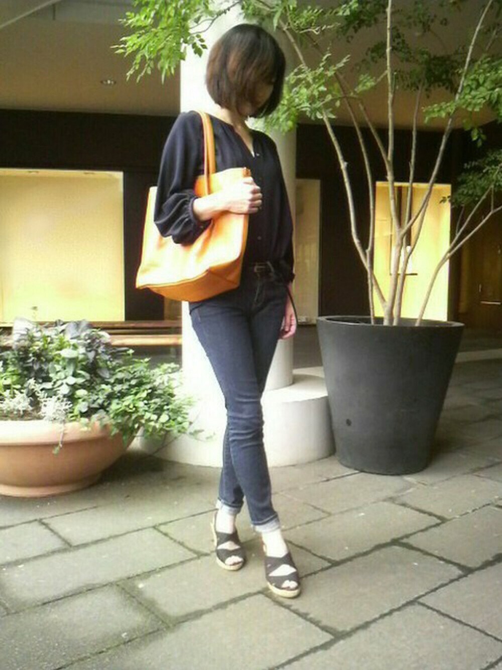 オレンジ系のトートバッグを着用したレディースの秋コーディネートの1枚目の写真