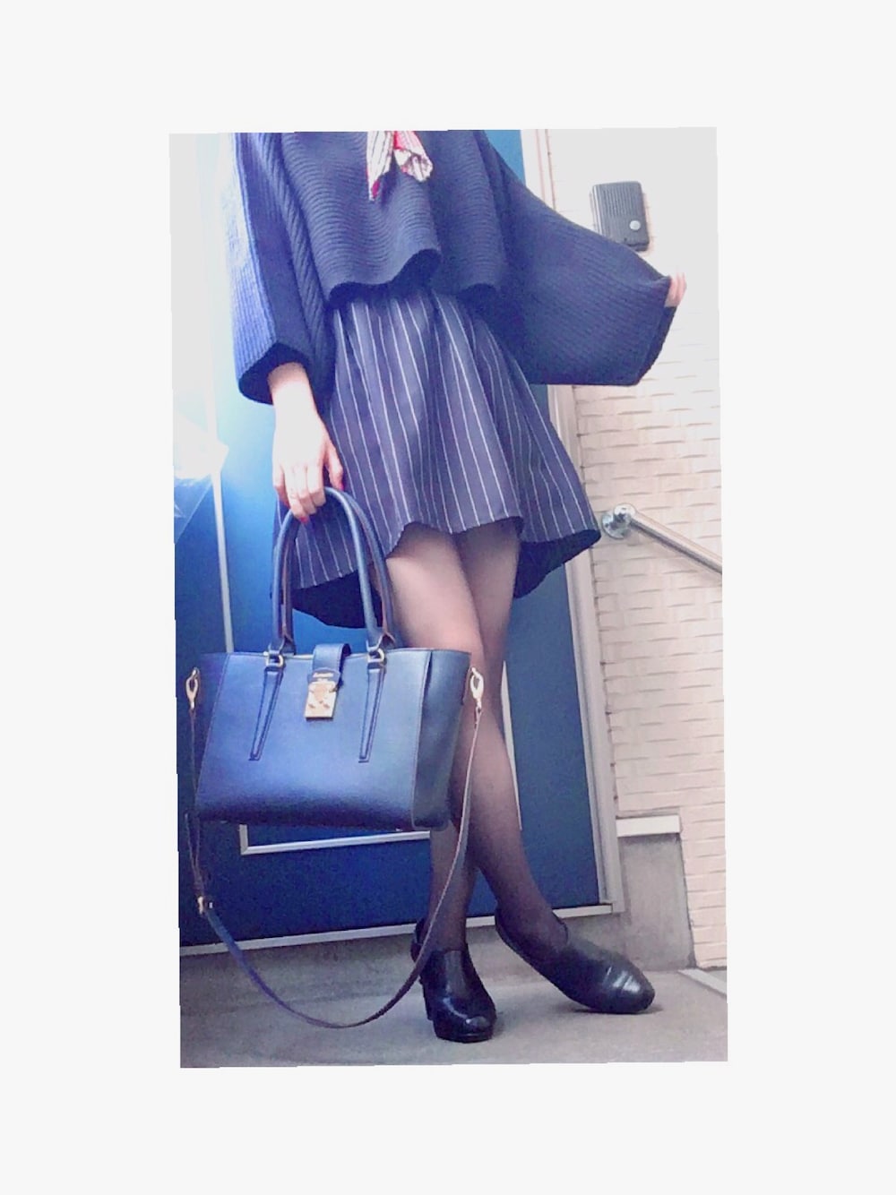 ブルー系のショルダーバッグ、ブラック系のブーティ、ブルー系のスカートを着用したレディースの秋コーディネートの1枚目の写真