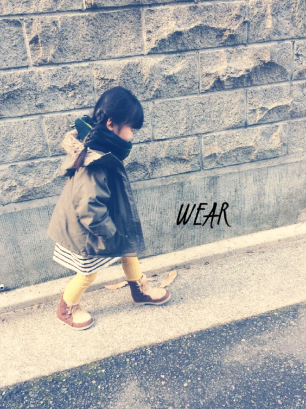 グリーン系のミリタリージャケット、ホワイト系のワンピース、ブラウン系のブーツを着用したキッズの冬コーディネートの1枚目の写真