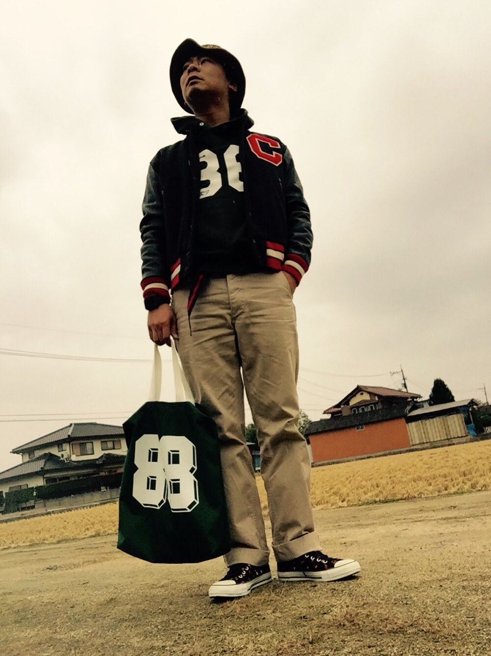 グリーン系のTシャツ/カットソー、ベージュ系のチノパンツ、グリーン系のショルダーバッグを着用したメンズの秋コーディネートの1枚目の写真