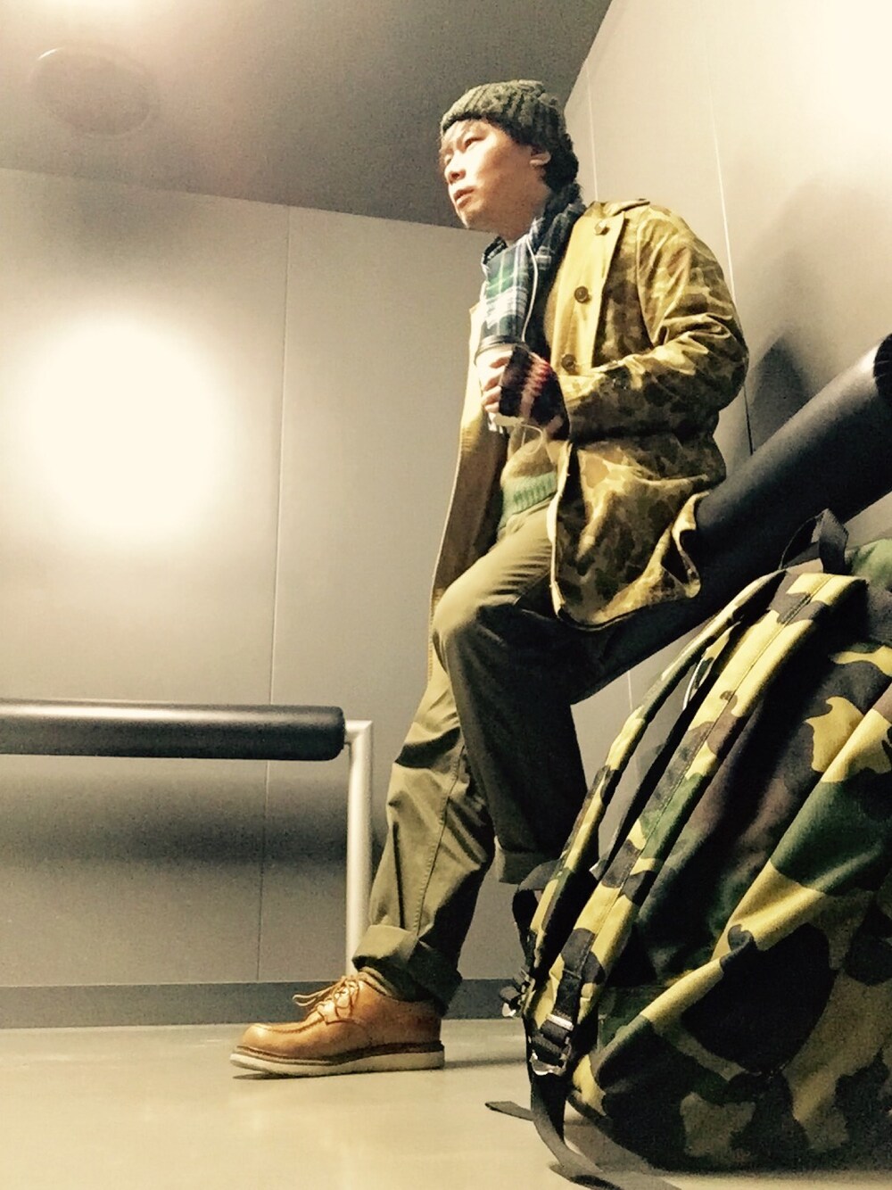 ベージュ系のステンカラーコート、ベージュ系のニット/セーター、グリーン系のその他パンツを着用したメンズの秋コーディネートの1枚目の写真