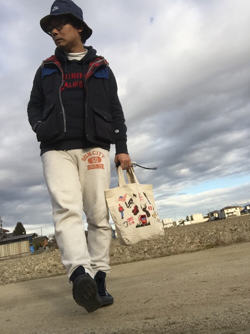 ブルー系のベスト、ブルー系のスウェット、グレー系のパンツを着用したメンズの冬コーディネートの1枚目の写真