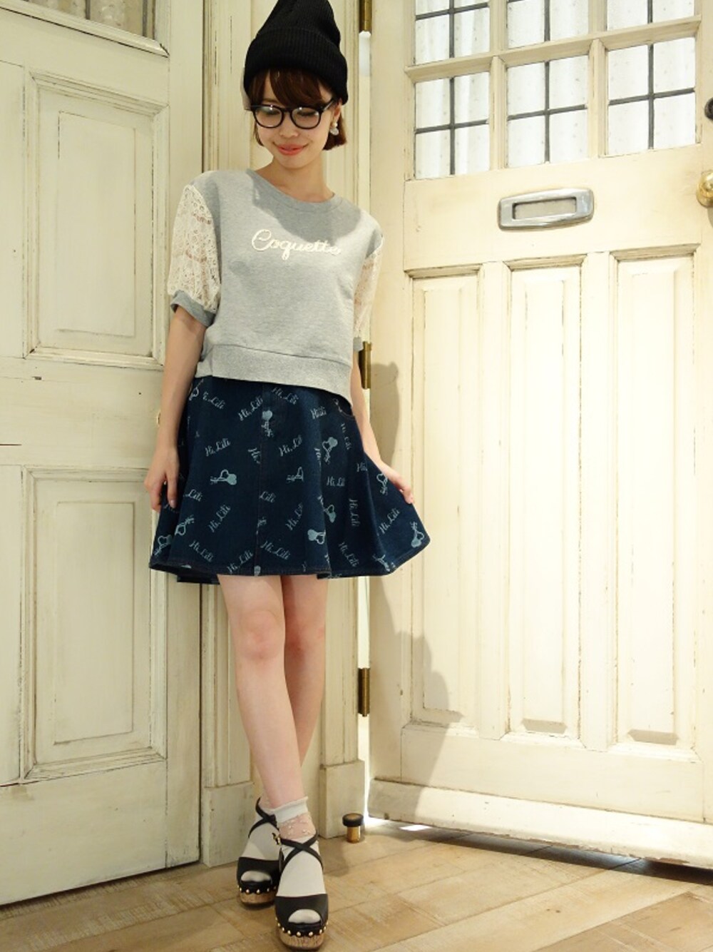 ホワイト系のスウェット、ブルー系のデニムスカート、ブラック系のサンダルを着用したレディースの夏コーディネートの1枚目の写真