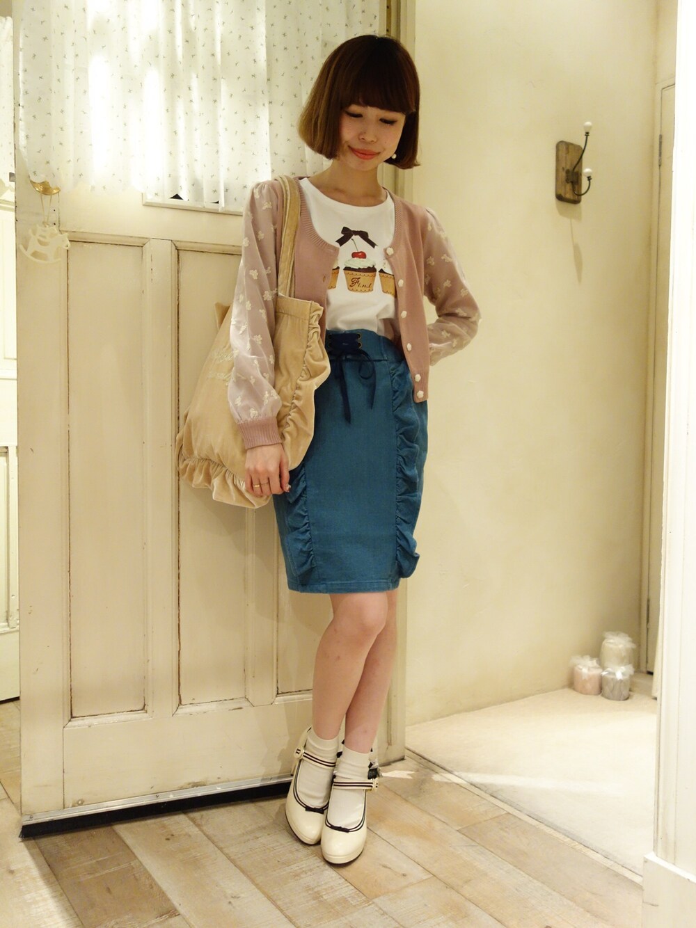 ベージュ系のトートバッグ、ピンク系のカーディガン/ボレロ、ホワイト系のTシャツ/カットソーを着用したレディースの夏コーディネートの1枚目の写真