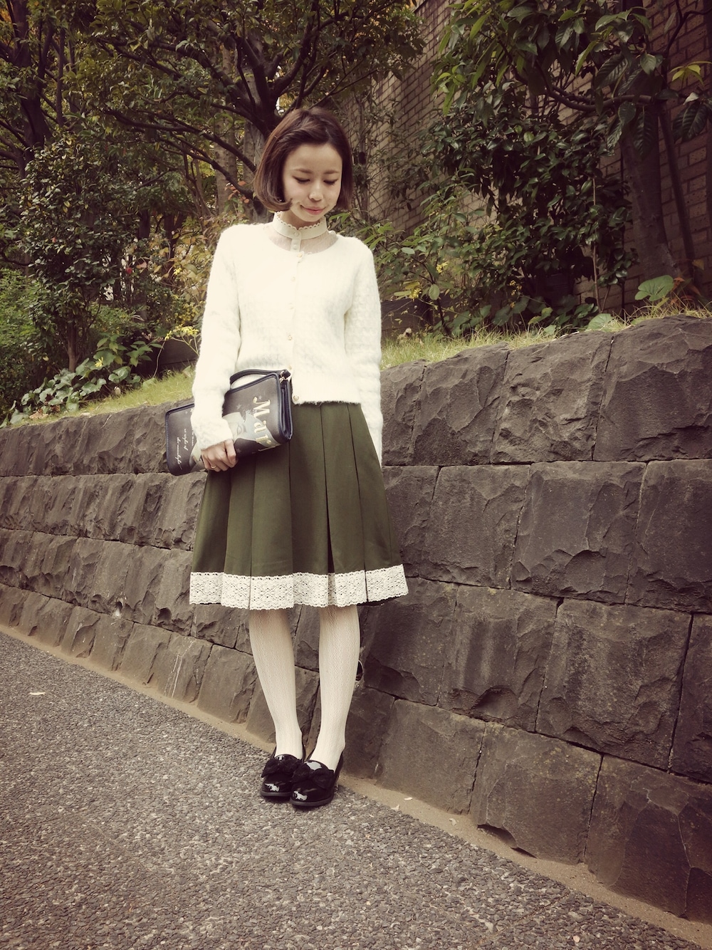 ホワイト系のカーディガン/ボレロ、グリーン系のスカート、ホワイト系のシャツ/ブラウスを着用したレディースの秋コーディネートの1枚目の写真