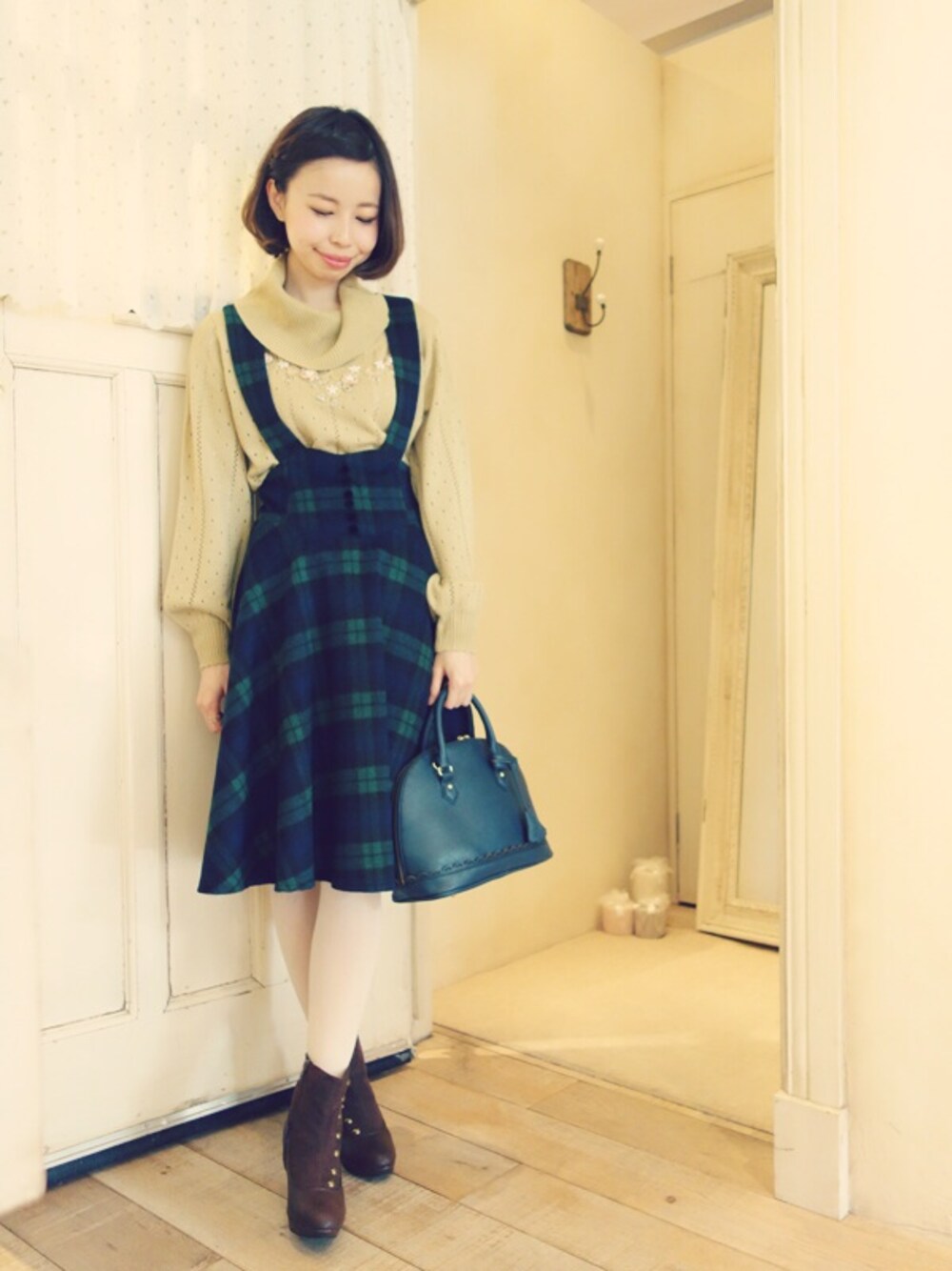 イエロー系のニット/セーター、グリーン系のスカート、グリーン系のボストンバッグを着用したレディースの冬コーディネートの1枚目の写真