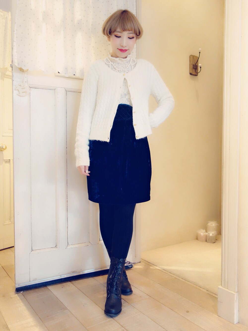 ホワイト系のカーディガン/ボレロ、ホワイト系のワンピース、ブラック系のブーツを着用したレディースの冬コーディネートの1枚目の写真