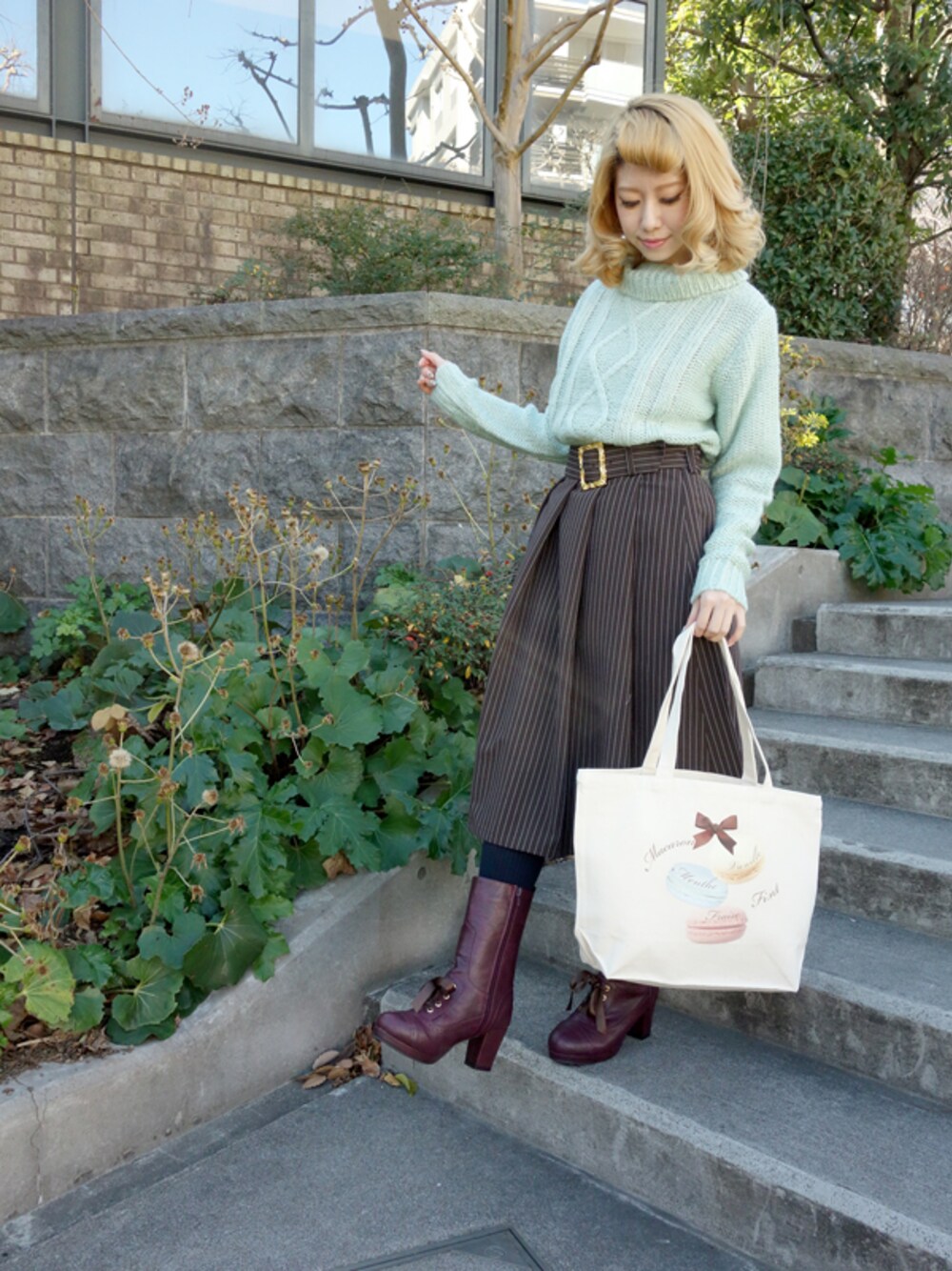 ブラック系のスカート、グリーン系のブーツ、ホワイト系のニット/セーターを着用したレディースの冬コーディネートの1枚目の写真