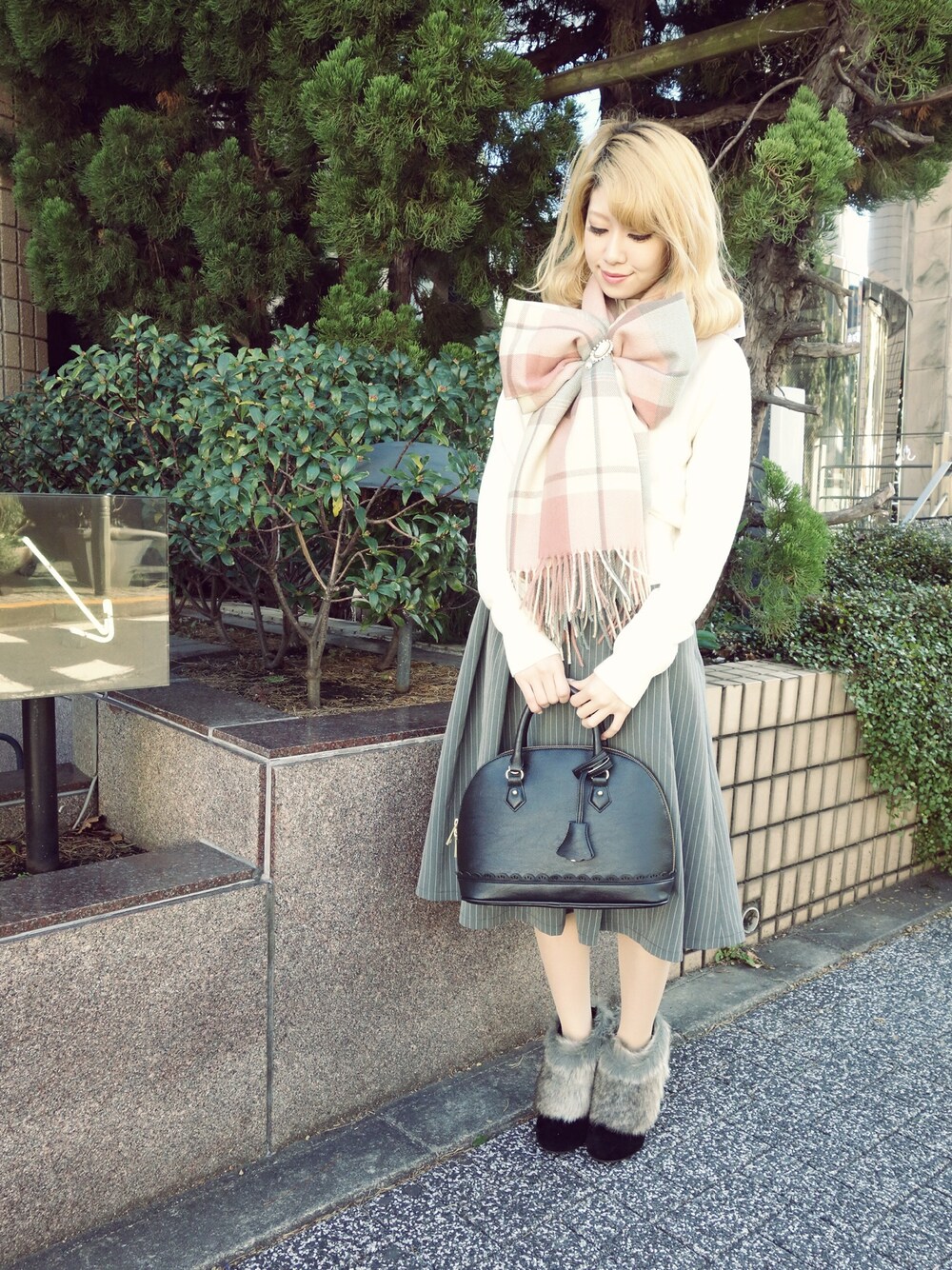 ブラック系のスカート、ブラック系のブーティ、グリーン系のボストンバッグを着用したレディースの冬コーディネートの1枚目の写真