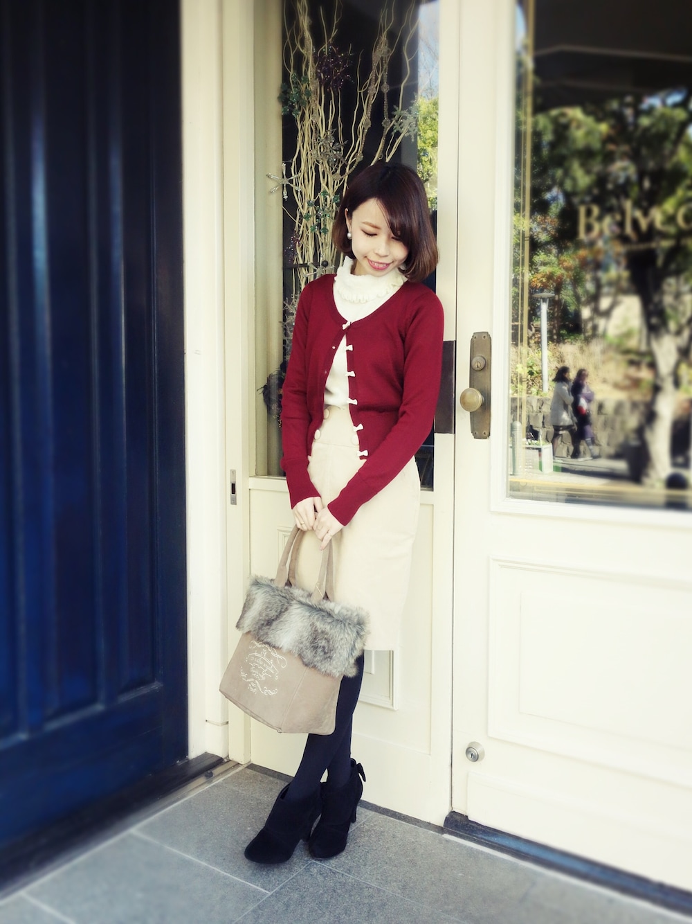 ブラウン系のトートバッグ、ブラック系のブーティ、レッド系のカーディガン/ボレロを着用したレディースの冬コーディネートの1枚目の写真