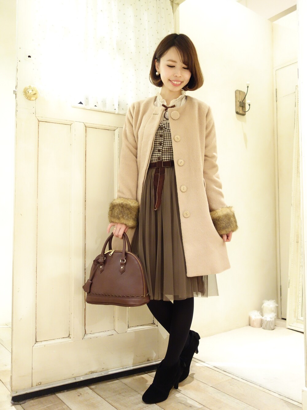 ブラック系のブーティ、ホワイト系のシャツ/ブラウス、ブルー系のボストンバッグを着用したレディースの冬コーディネートの1枚目の写真