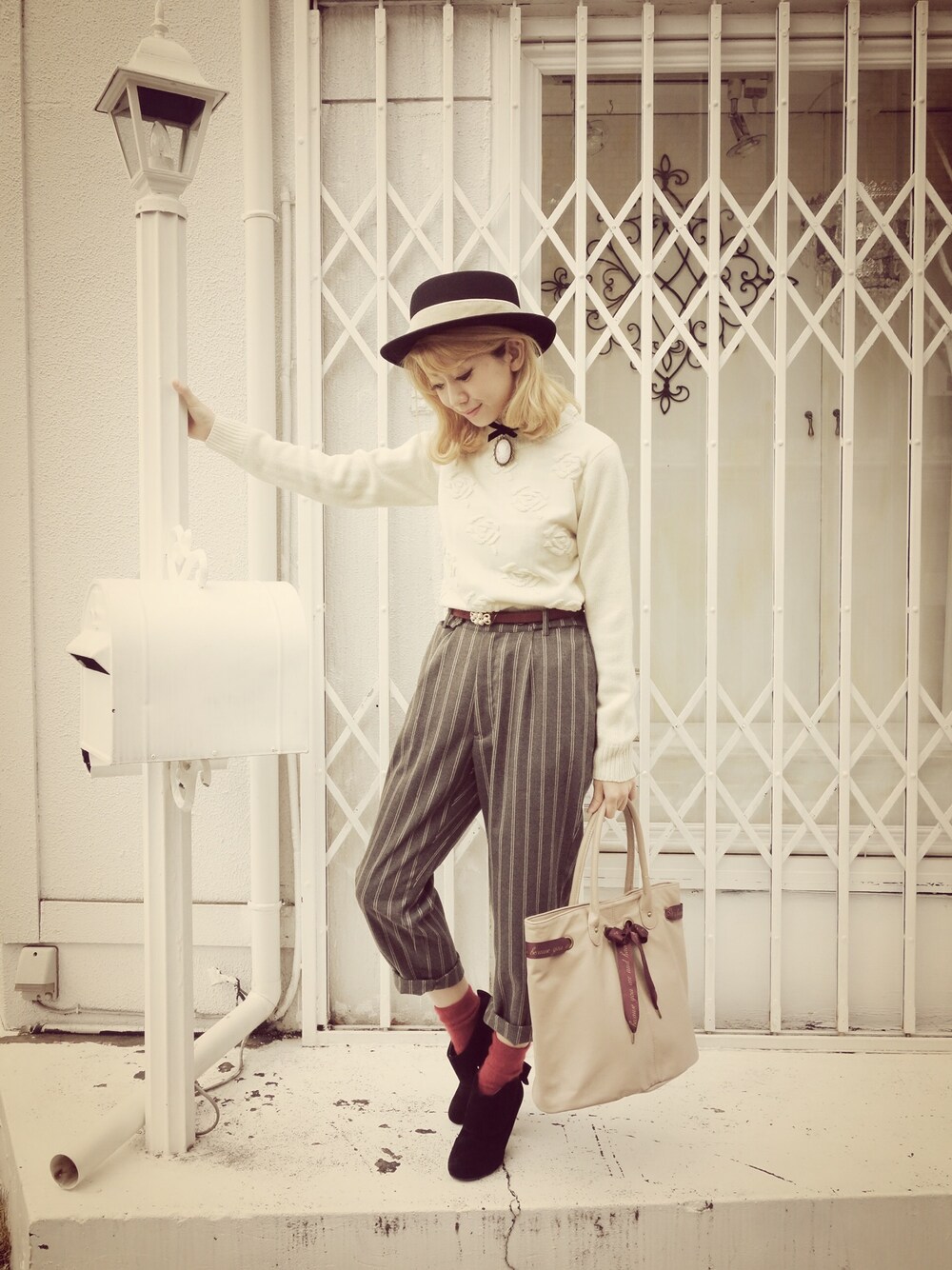 ブラウン系のトートバッグ、ブラック系のブーティ、ホワイト系のニット/セーターを着用したレディースの冬コーディネートの1枚目の写真