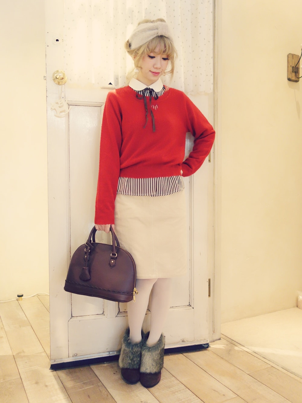 レッド系のニット/セーター、ホワイト系のスカート、ブラウン系のシャツ/ブラウスを着用したレディースの冬コーディネートの1枚目の写真