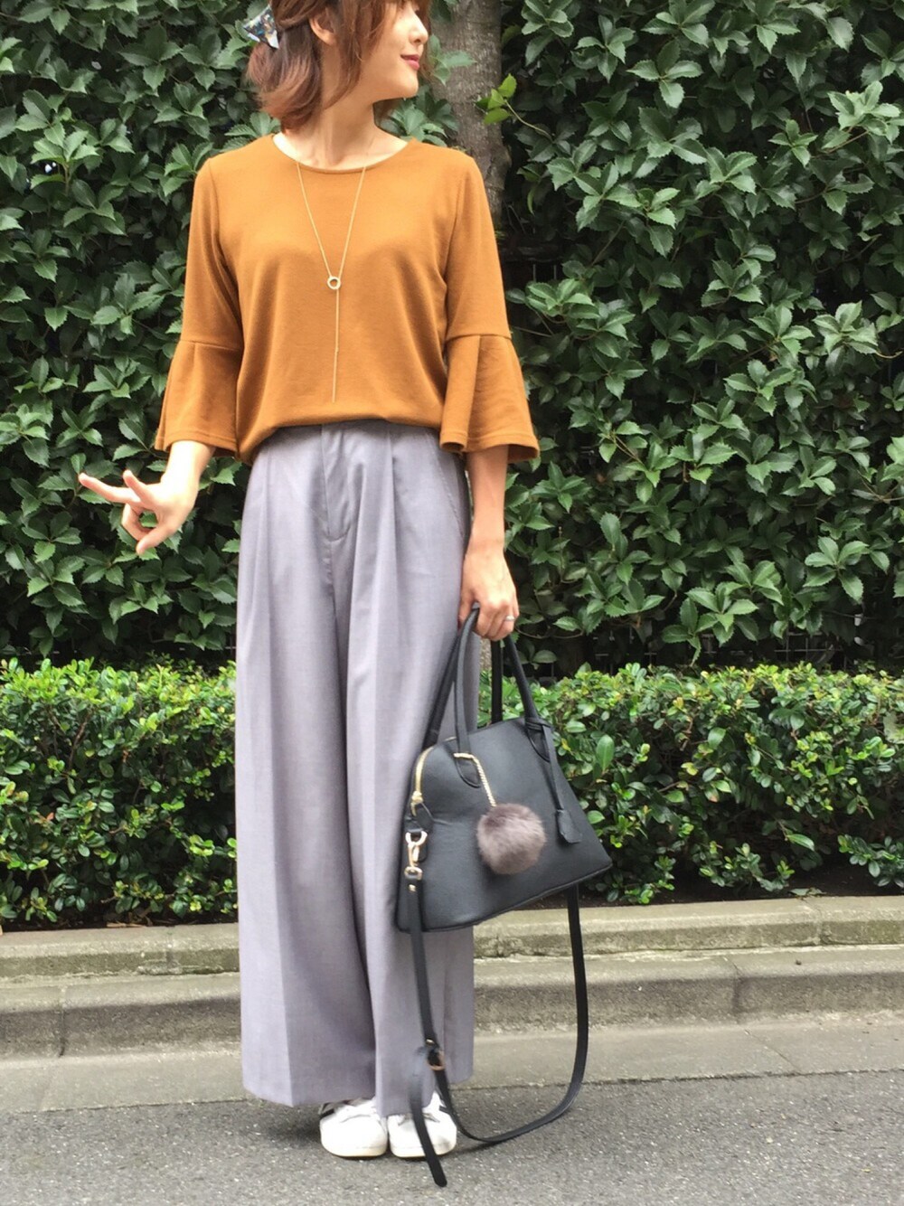 イエロー系のニット/セーター、グレー系のその他パンツ、ホワイト系のスニーカーを着用したレディースの秋コーディネートの1枚目の写真