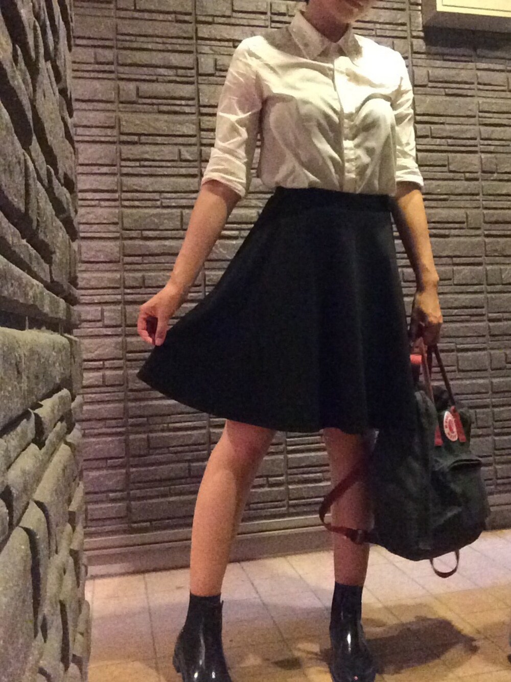 グリーン系のスーツケース/キャリーバッグ、ブラック系のスカート、ブラック系のレインシューズを着用したレディースの夏コーディネートの1枚目の写真