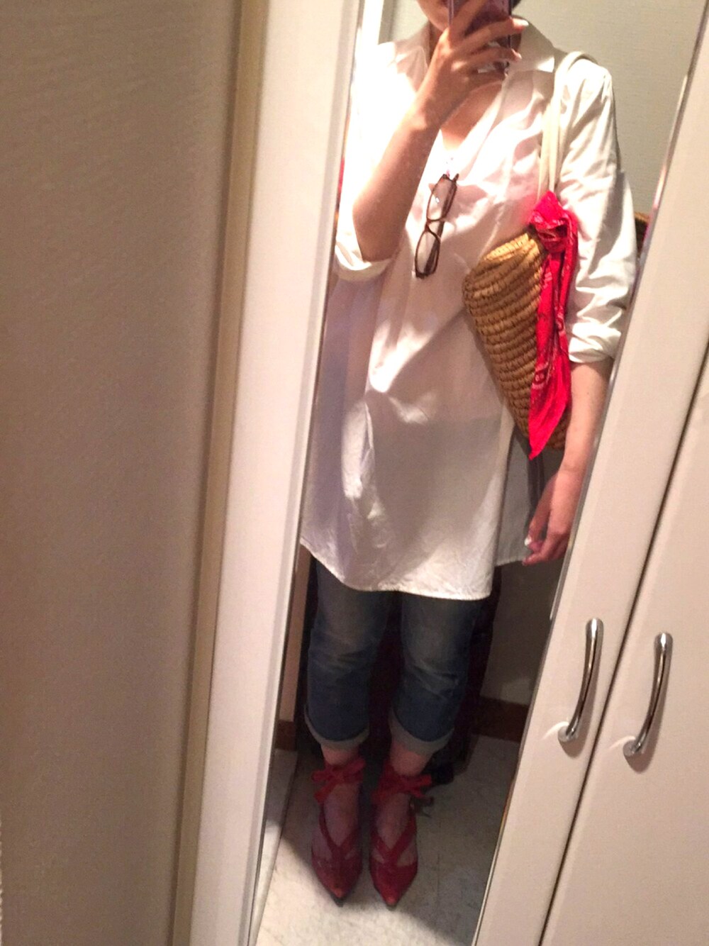 ホワイト系のシャツワンピース、レッド系のパンプス、ベージュ系のかごバッグを着用したレディースの春コーディネートの1枚目の写真