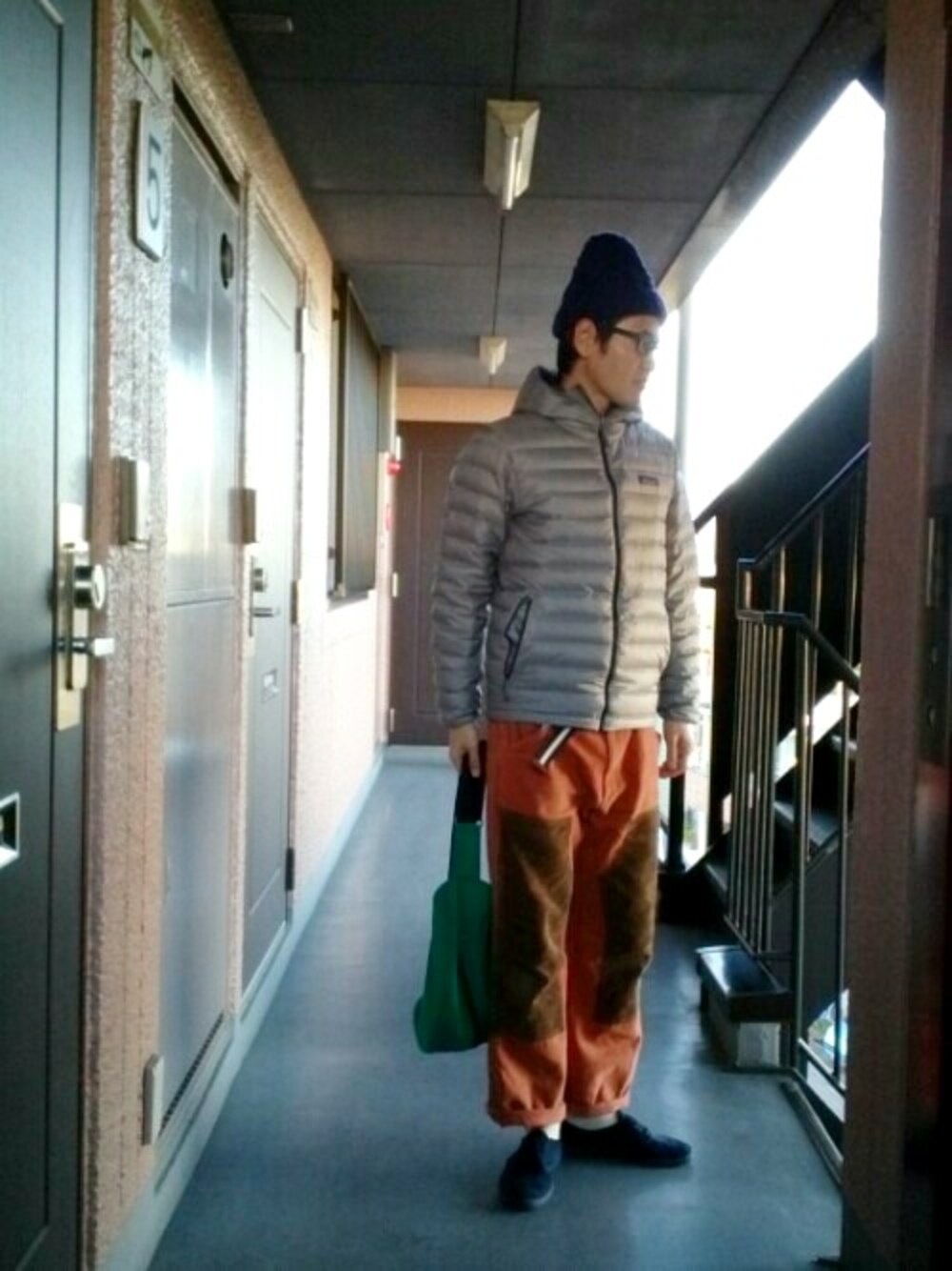 グレー系のダウンジャケット/コート、ブラウン系のその他パンツ、ブルー系のスニーカーを着用したメンズの冬コーディネートの1枚目の写真