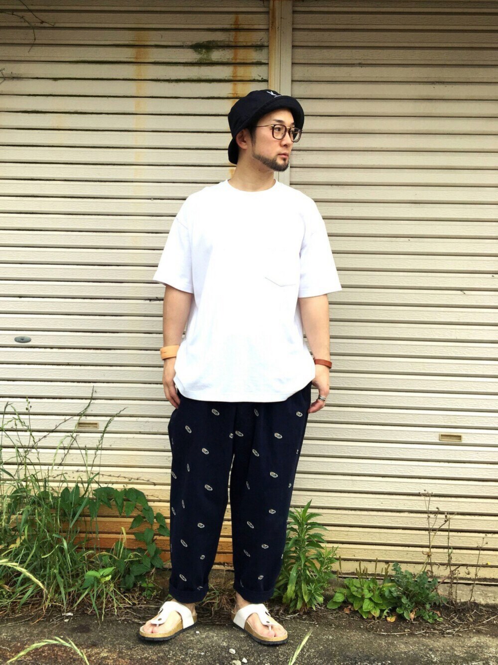ブルー系のチノパンツ、ブラック系のハット、ブラウン系のメガネを着用したメンズの春コーディネートの1枚目の写真
