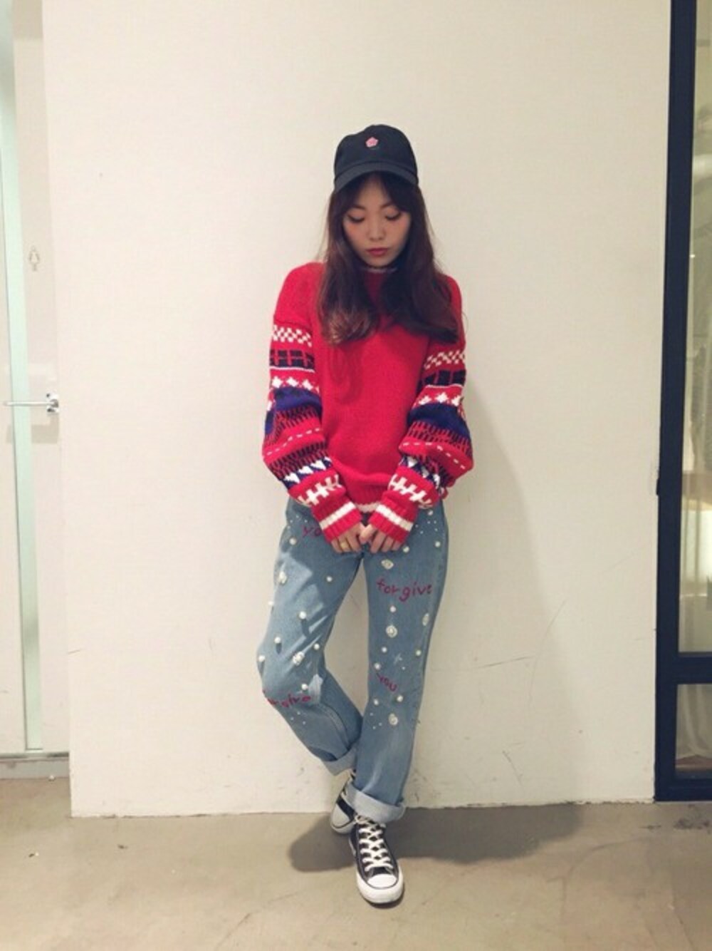 レッド系のニット/セーター、ブラック系のキャップを着用したレディースの冬コーディネートの1枚目の写真