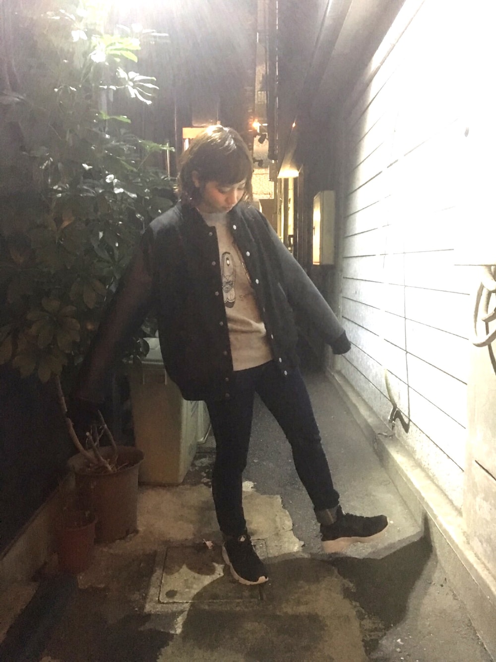 ブラック系のスタジャン、ブルー系のデニムパンツ、ブラック系のスニーカーを着用したレディースの秋コーディネートの1枚目の写真