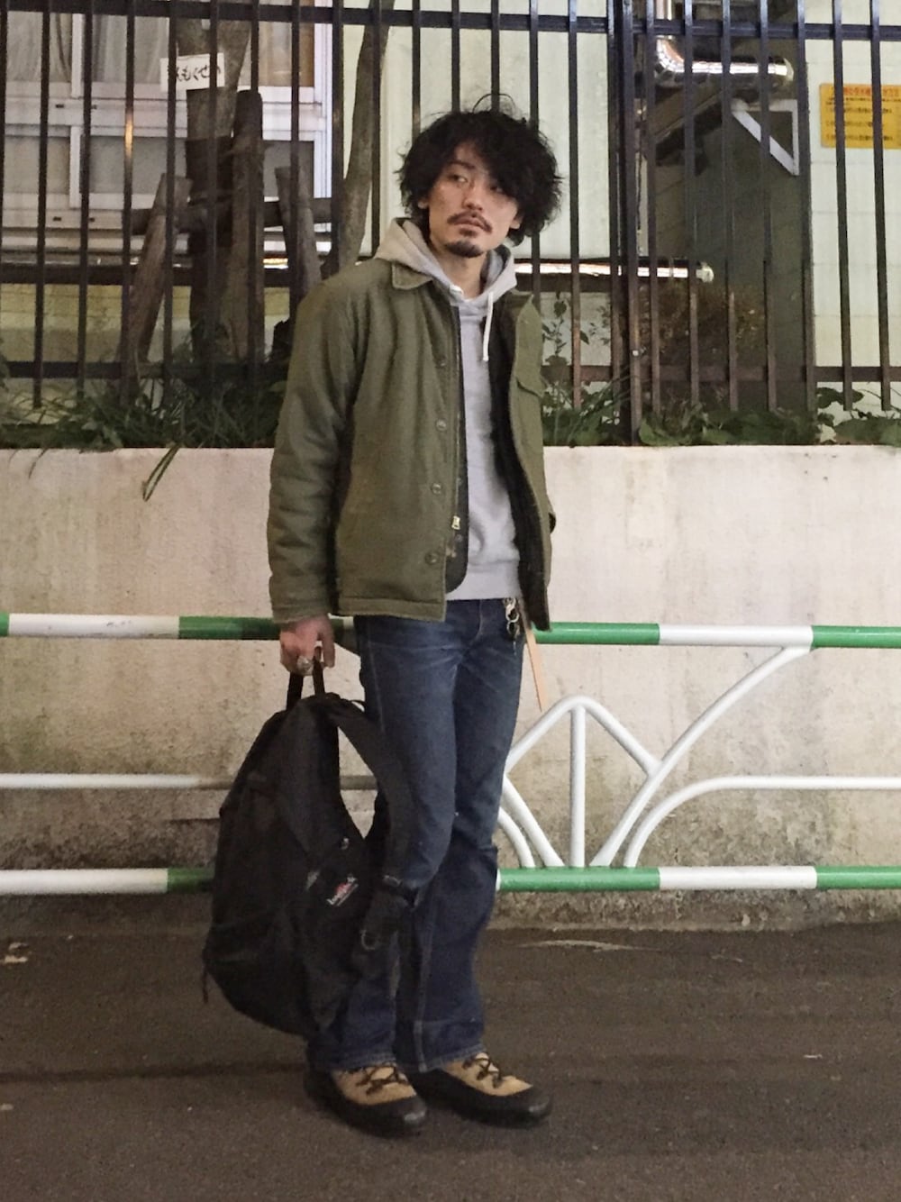 グリーン系のミリタリージャケット、グリーン系のベスト、グレー系のパーカーを着用したメンズの冬コーディネートの1枚目の写真