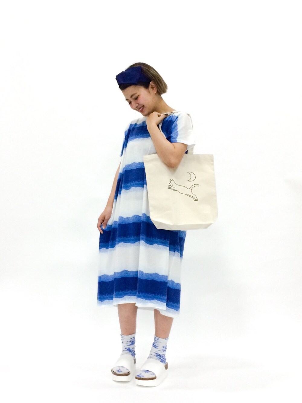 ブルー系のワンピース、ベージュ系のトートバッグ、ホワイト系のサンダルを着用したレディースの春コーディネートの1枚目の写真