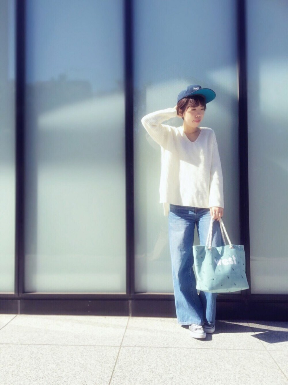 グレー系のスニーカー、ブルー系のデニムパンツ、ホワイト系のニット/セーターを着用したレディースの春コーディネートの1枚目の写真