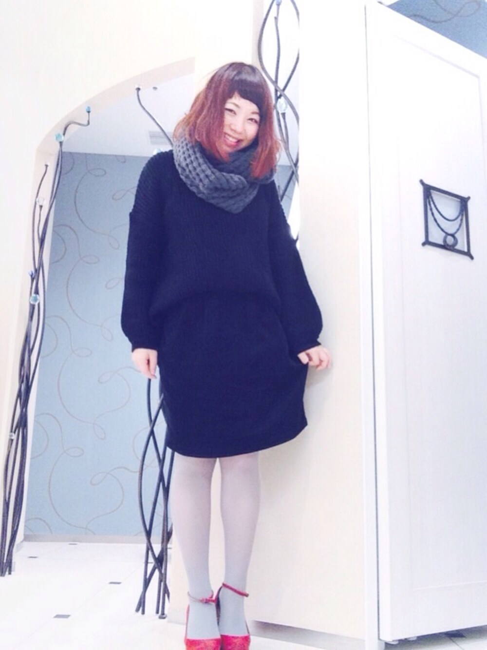 ブラック系のニット/セーター、ブラック系のスカート、レッド系のパンプスを着用したレディースの秋コーディネートの1枚目の写真