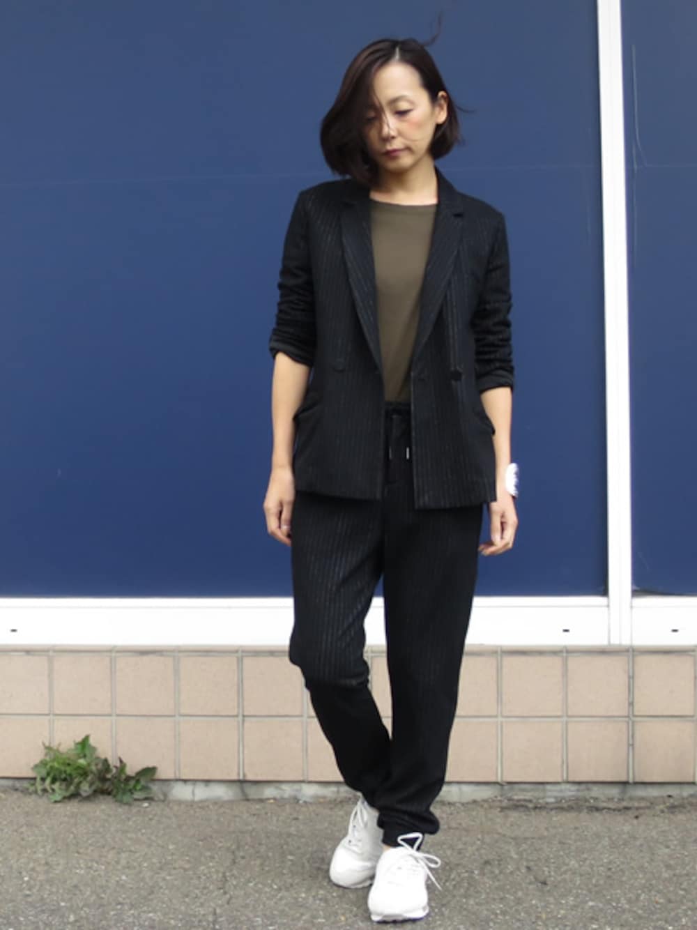 ブラック系のテーラードジャケット、ブラック系のその他パンツ、グリーン系のTシャツ/カットソーを着用したレディースの秋コーディネートの1枚目の写真
