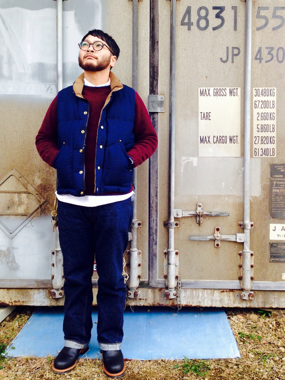 ブルー系のダウンベスト、レッド系のニット/セーター、ブルー系のデニムパンツを着用したメンズの冬コーディネートの1枚目の写真